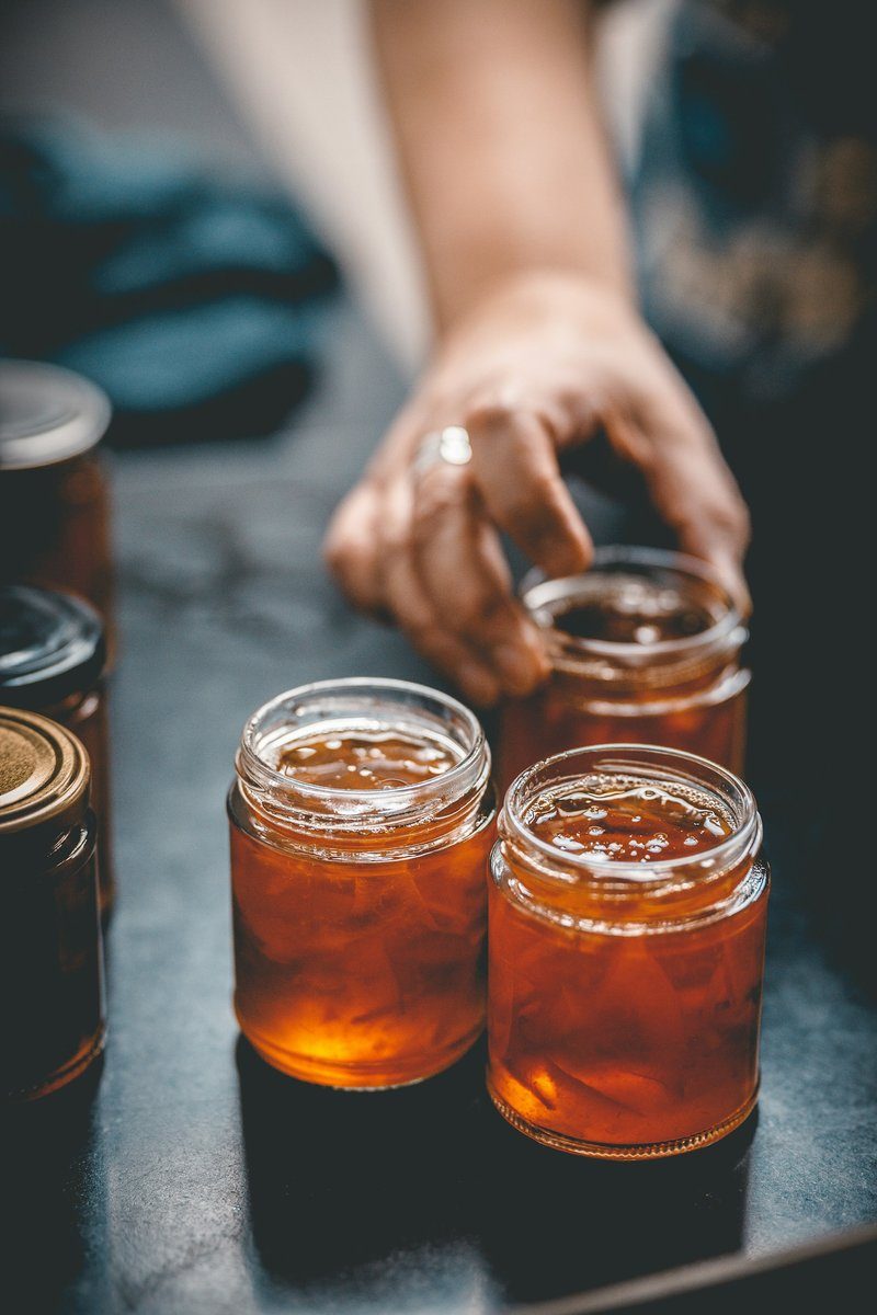 Main posant des pots de confiture sur une table sombre