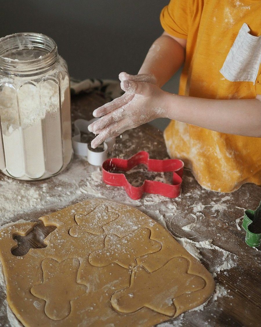 Mains d'enfant farinées au-dessus d'une pâte et d'emporte-pièces