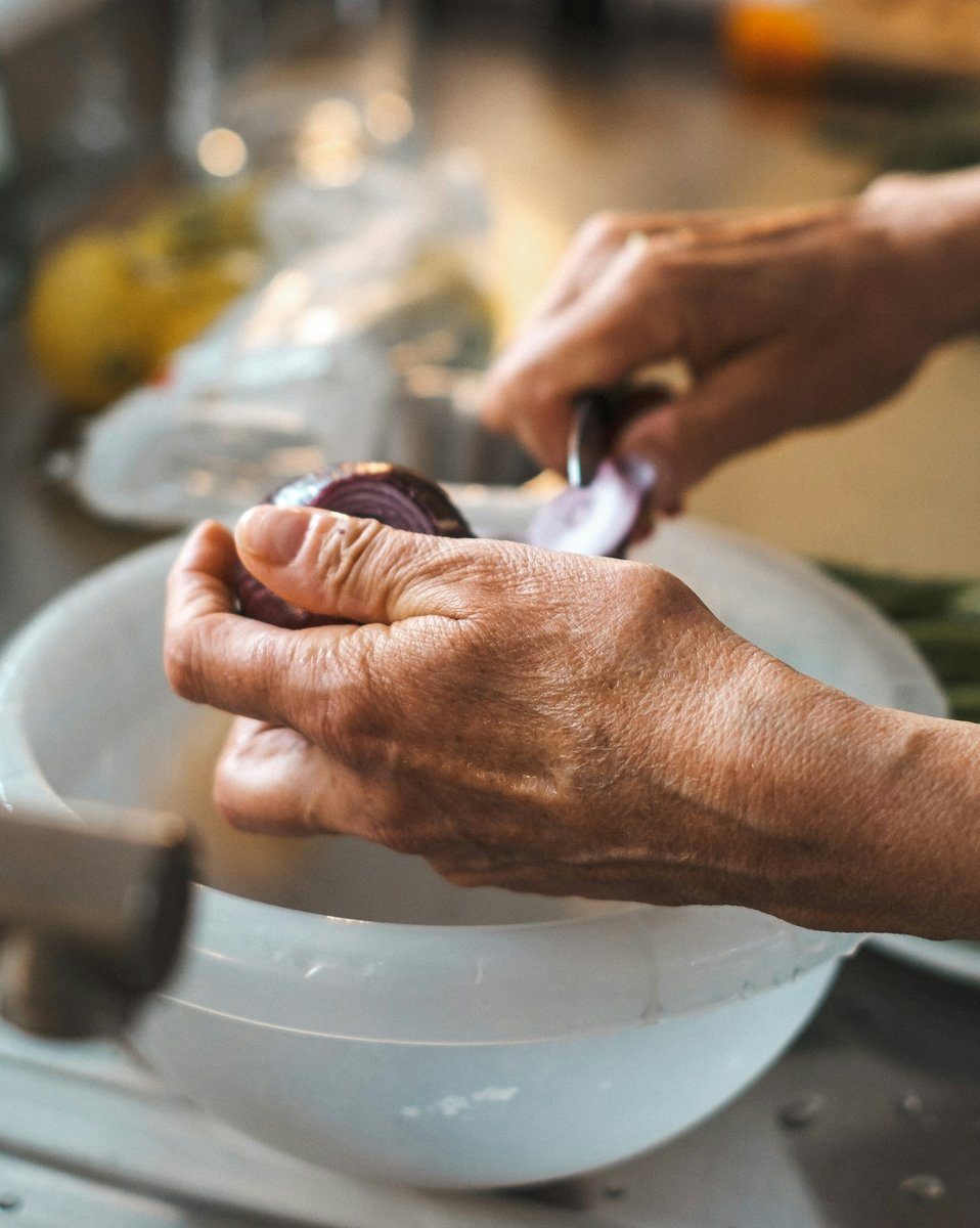 Mains âgées épluchant un oignon au-dessus d'un bol