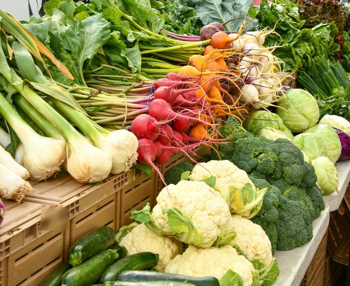 Étal de marché avec chou-fleur, brocoli, radis et oignons nouveaux