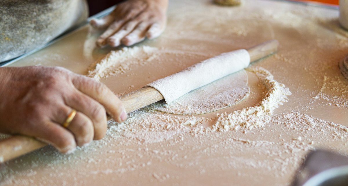 Mains âgées étalant une pâte au rouleau sur une table farinée